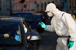 Un conducteur de voiture communique avec un travailleur de la santé au point de contrôle du service au volant pendant l’épidémie de coronavirus.