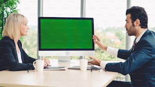 Des gens d’affaires dans la salle de conférence avec écran vert, une télévision à clé chromatique ou un ordinateur sur la table du bureau. Groupe diversifié d’hommes et de femmes d’affaires en réunion par vid�éoconférence.