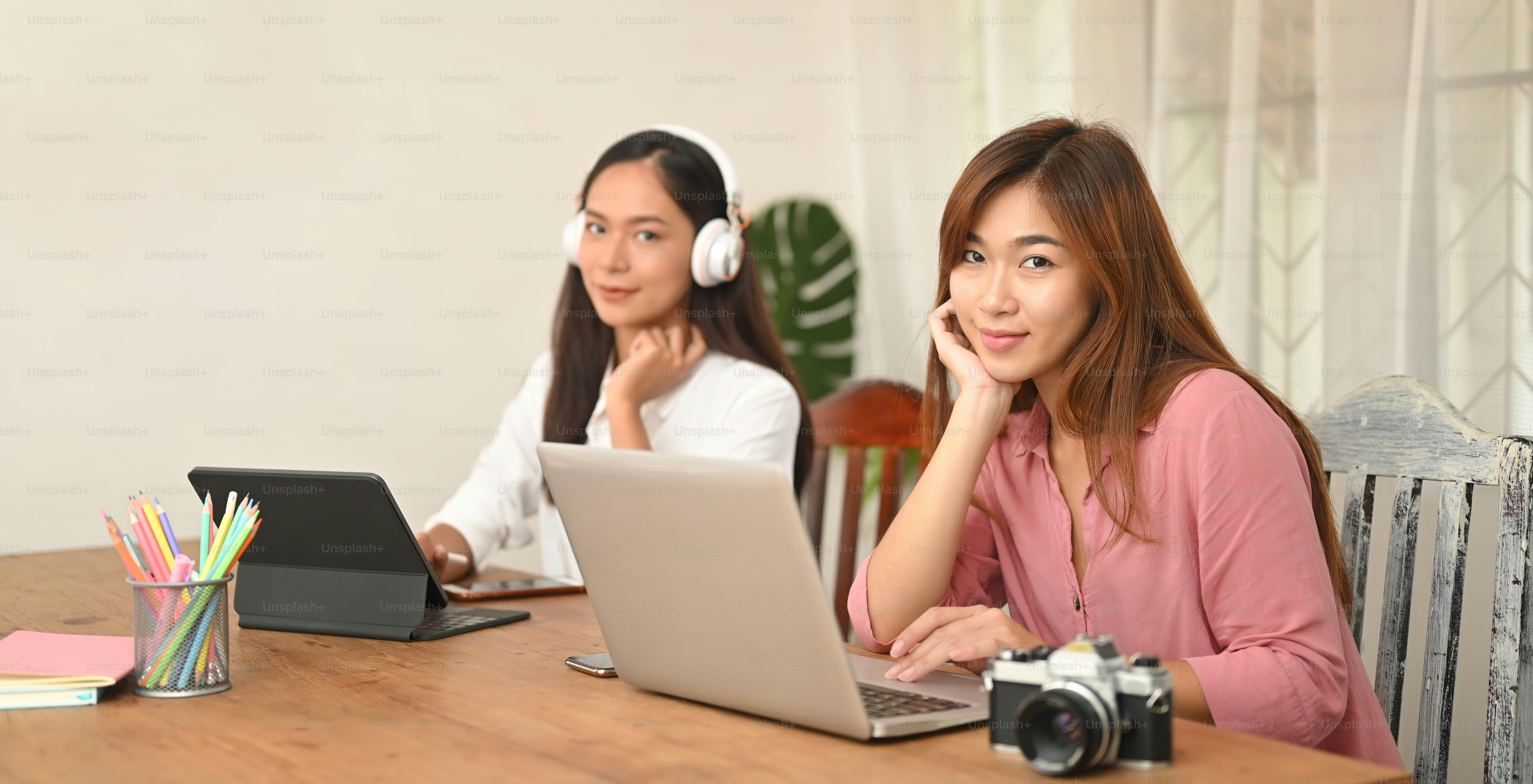 Photographer Women are working together with a computer tablet and laptop at the wooden working desk.