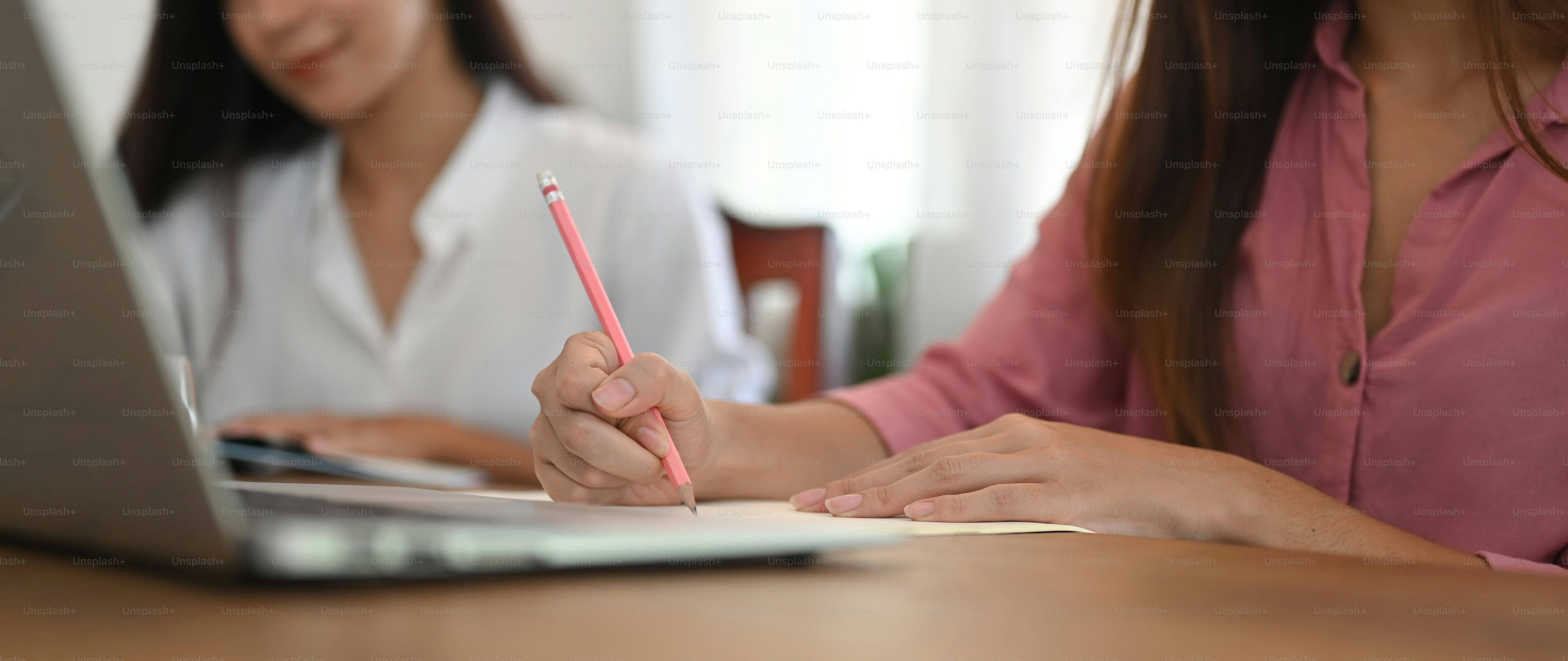 La imagen recortada de las mujeres funciona junto con una computadora portátil en el escritorio de trabajo de madera.