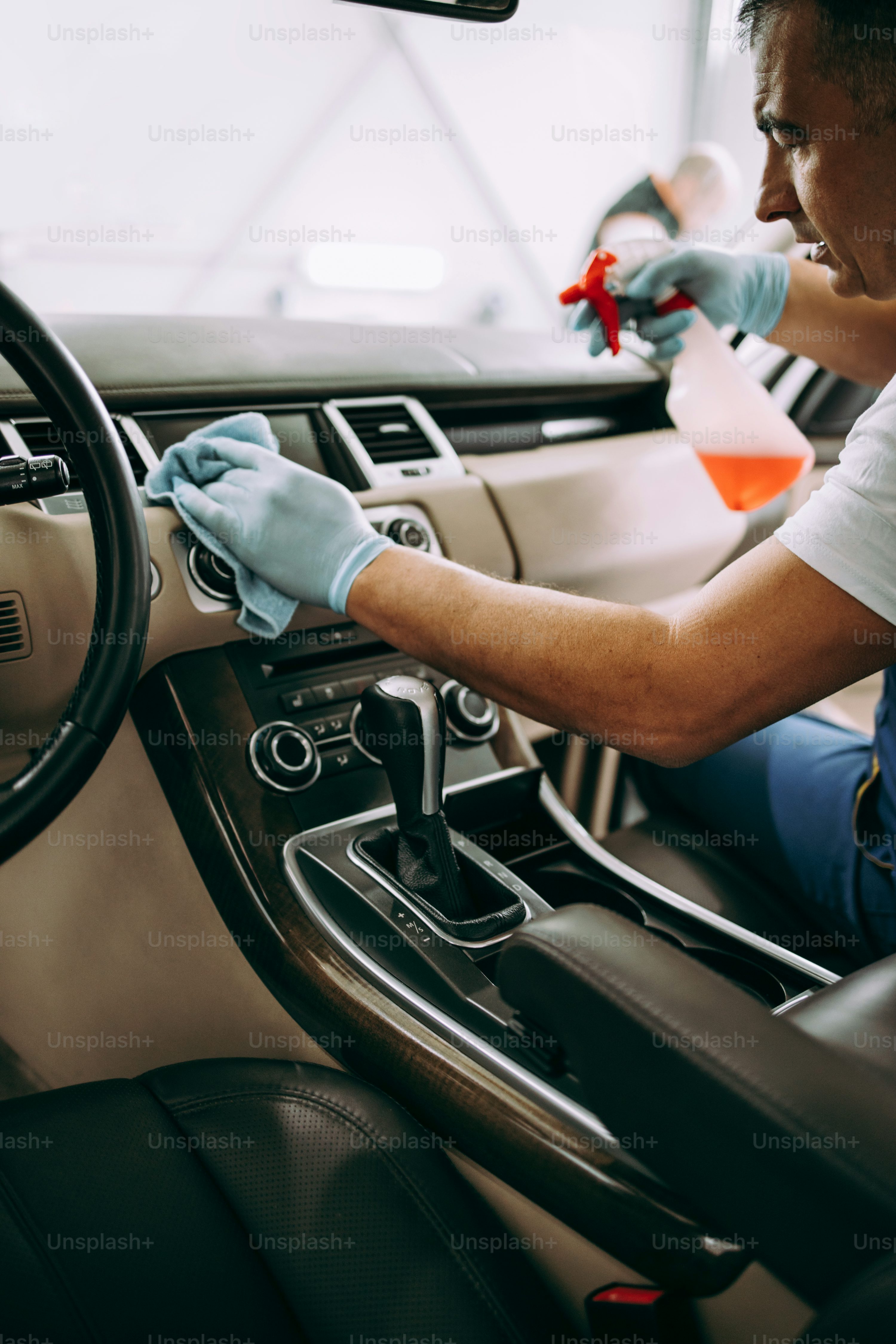 Car wash service worker wet cleaning expensive and luxurious vehicle interior and seats
