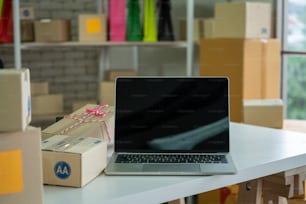 Laptop computer with empty screen on shipping box background. Concept of online retail store, delivery order and customer service.