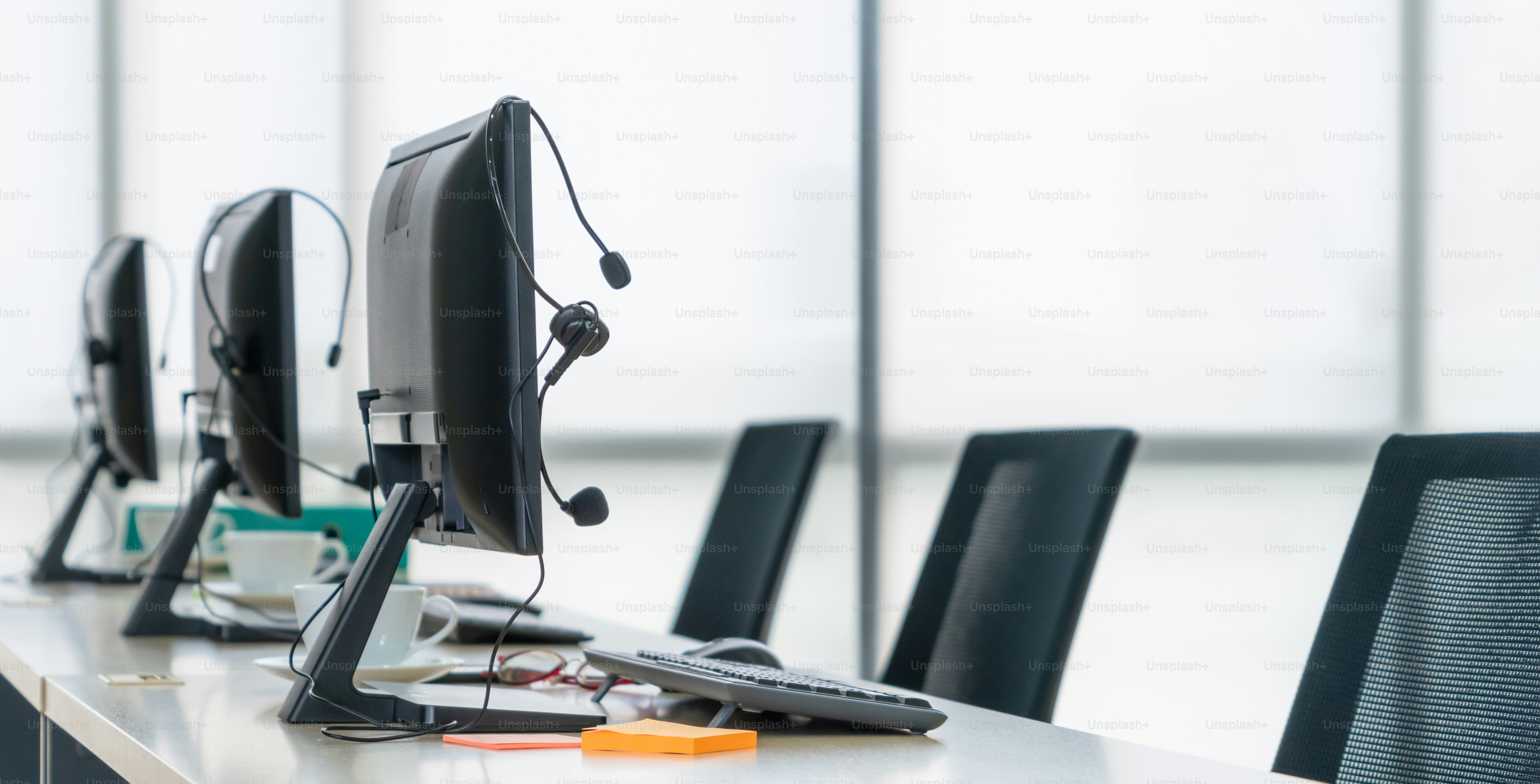 Call center computers and headsets all in office. Telemarketing, customer support agent provide service on telephone video conference call.