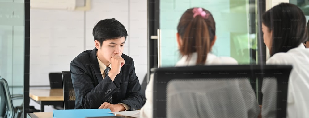 Women are talking with the Loan department staff while sitting together at the wooden table.