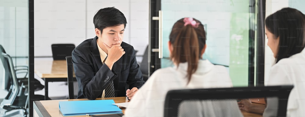 Women are talking with the Loan department staff while sitting together at the wooden table.