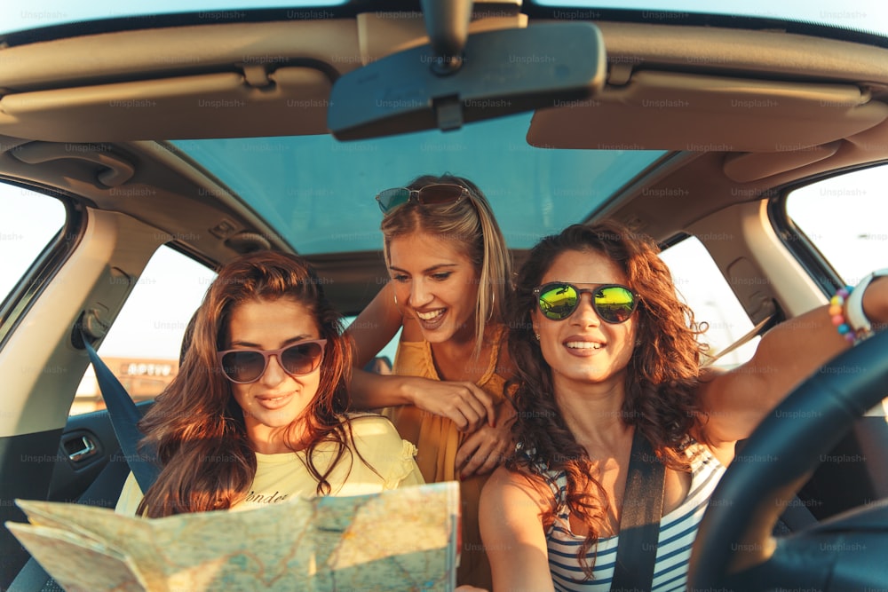 Three female friends enjoying traveling at vacation in the car.