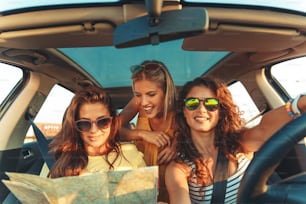 Three female friends enjoying traveling at vacation in the car.