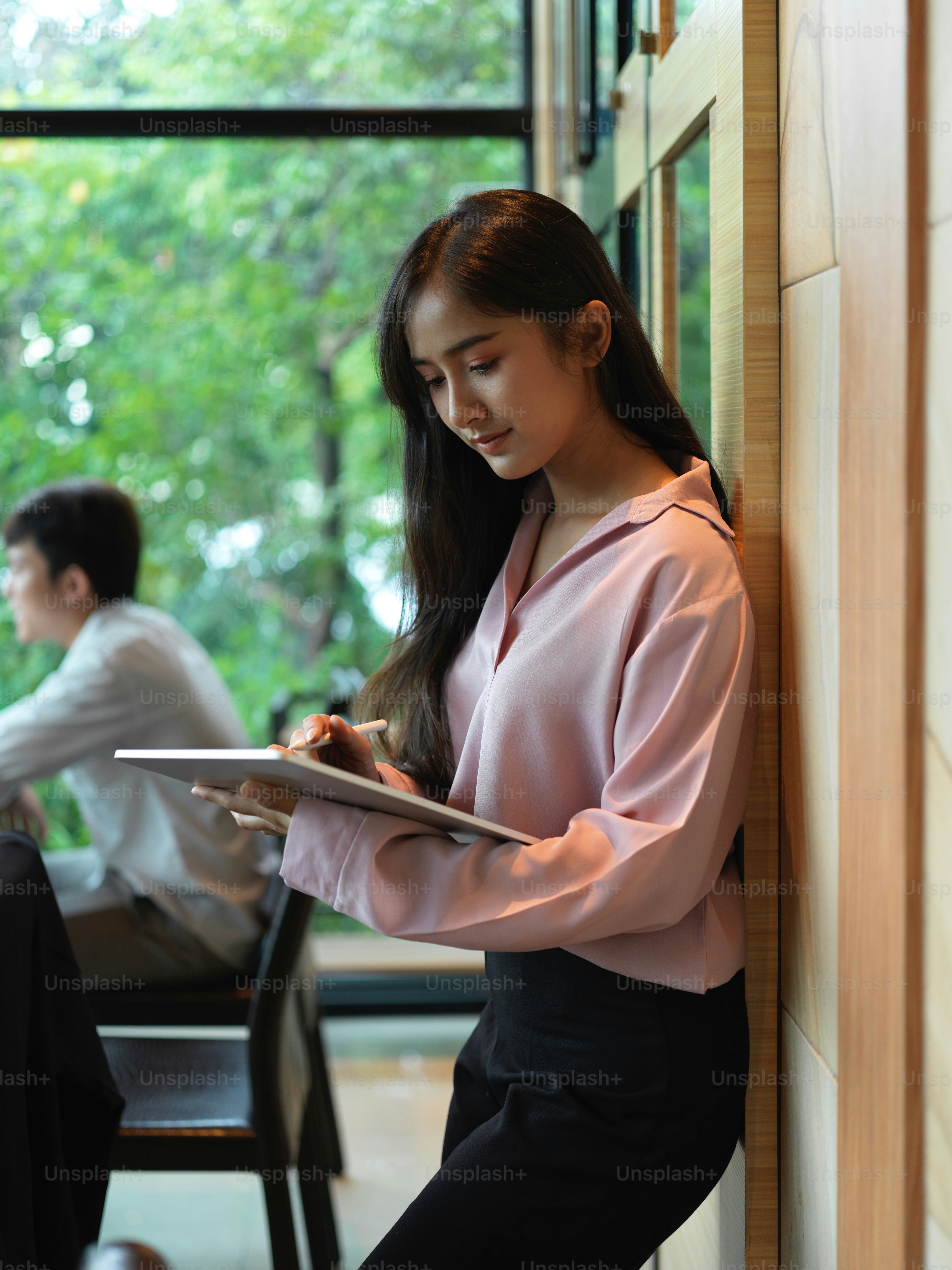 Portrait of businesswoman working with digital tablet while standing in modern meeting room