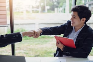 Young asian businessman partners fist bump showing cooperation and success at work.