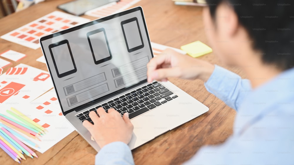 Imagem recortada de um homem está usando um laptop de computador com um ícone de interface na tela na mesa de madeira.