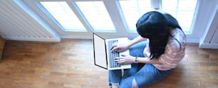 Top view of the woman is using a computer laptop on the living room floor.