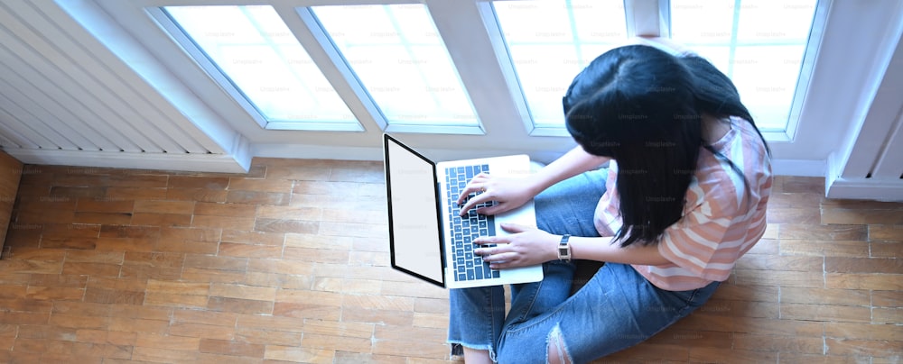 Top view of the woman is using a computer laptop on the living room floor.