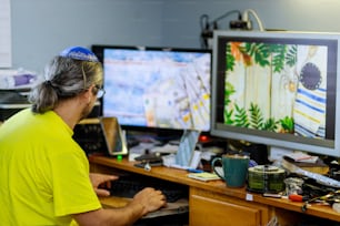 Diseñador de hombre judío que trabaja en casa en su mecanografía de mensajes de texto en la computadora en una mesa de madera en el escritorio de la oficina