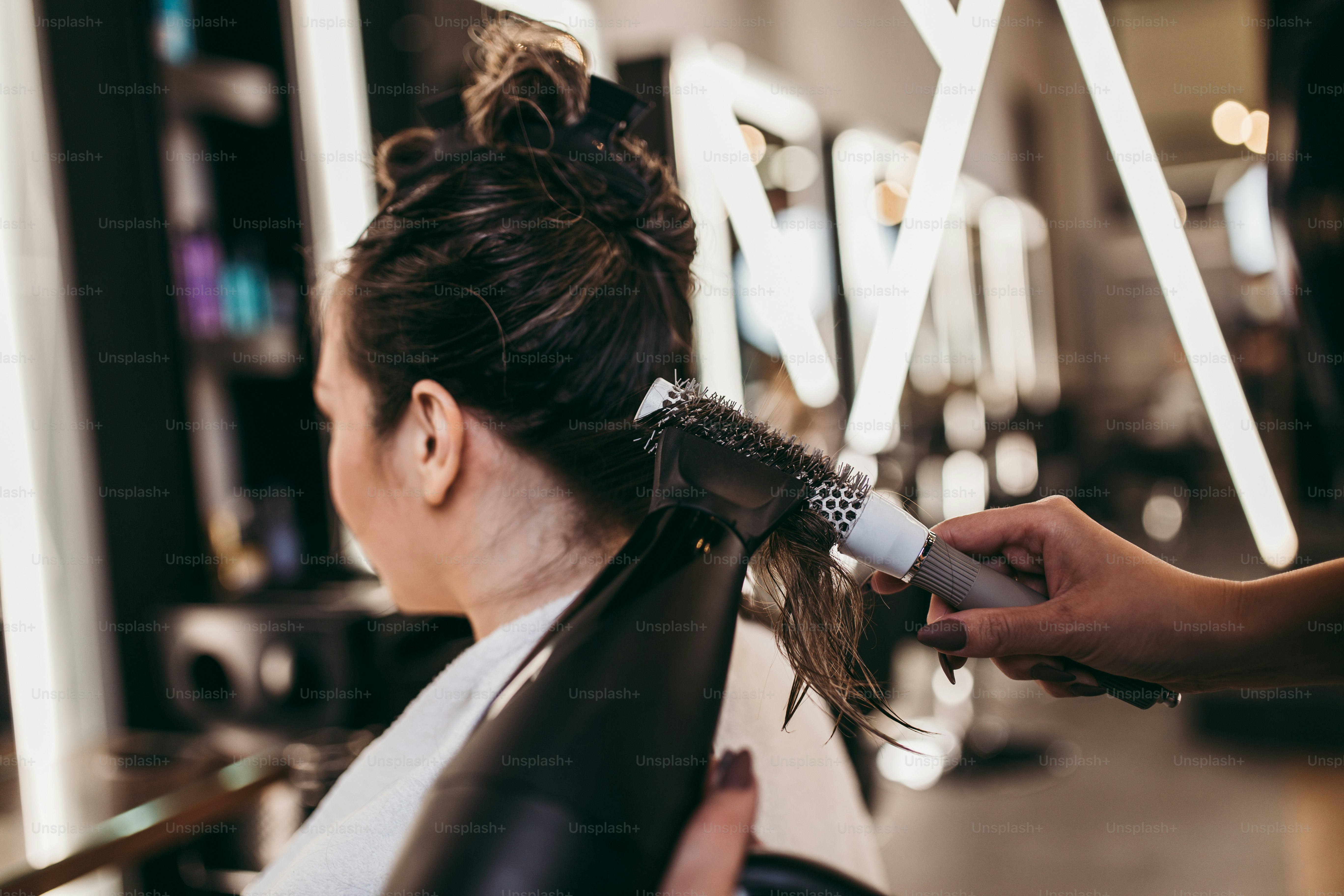Beautiful brunette woman with long hair at the beauty salon getting a hair blowing. Hair salon styling concept.