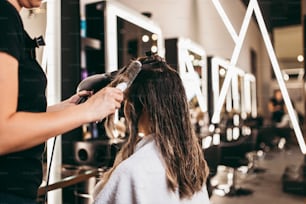 Beautiful brunette woman with long hair at the beauty salon getting a hair blowing. Hair salon styling concept.