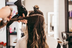 Belle femme brune aux cheveux longs au salon de beauté se faisant souffler les cheveux. Concept de coiffure de salon de coiffure.
