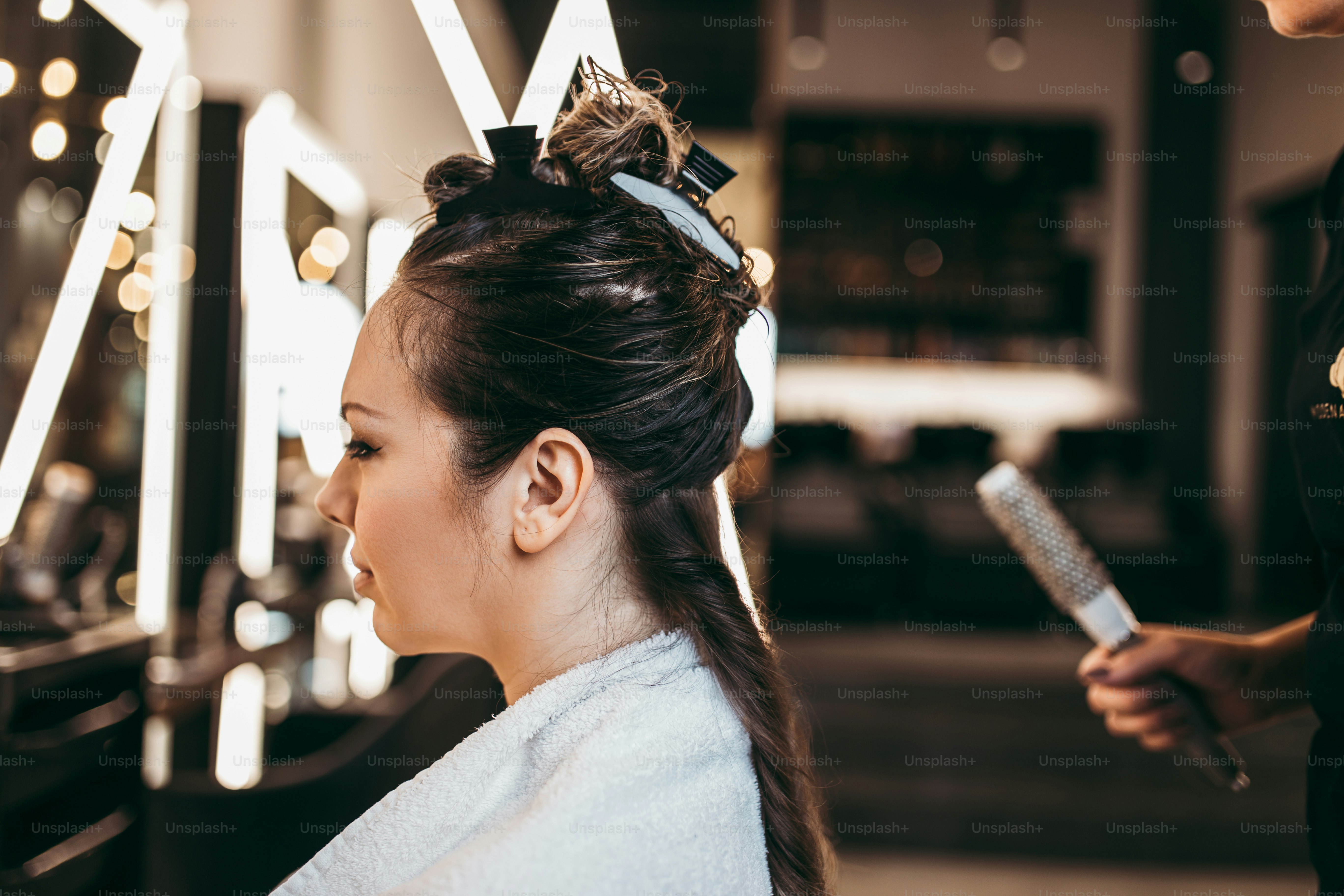 Beautiful brunette woman with long hair at the beauty salon getting a hair blowing. Hair salon styling concept.