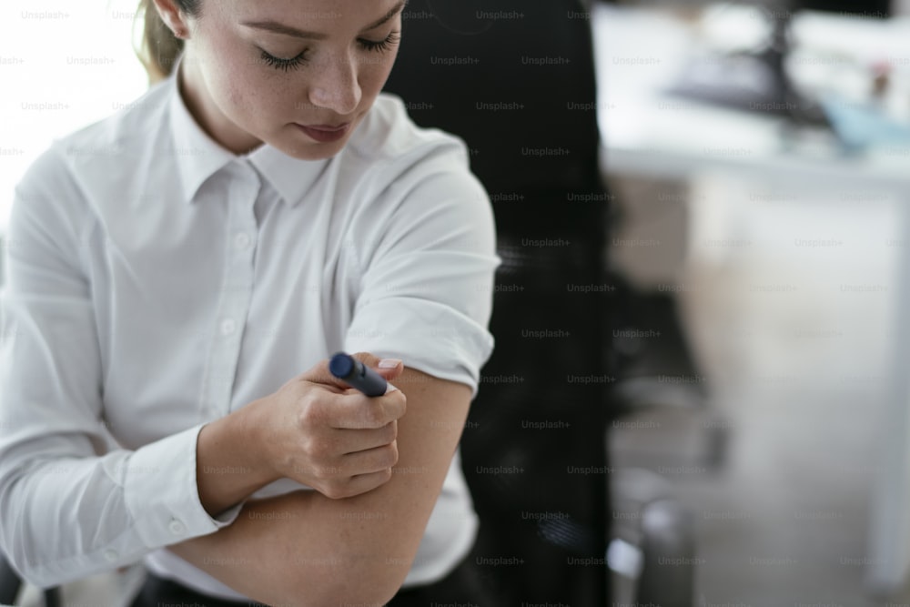 Businesswoman is giving herself an injection of insulin.