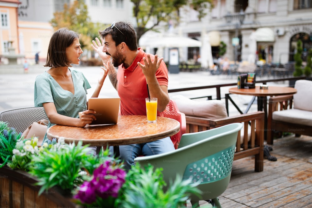 Unhappy young couple arguing in cafe. People, cheating, conflict, relationship problems concept.