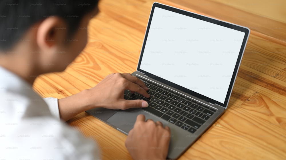 Cropped image of hands is using a computer laptop at the wooden working desk.
