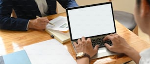 Cropped image of hands is using a computer laptop at the wooden working desk.