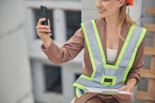 Cropped photo of a smiling young female engineer holding her gadget in front of her