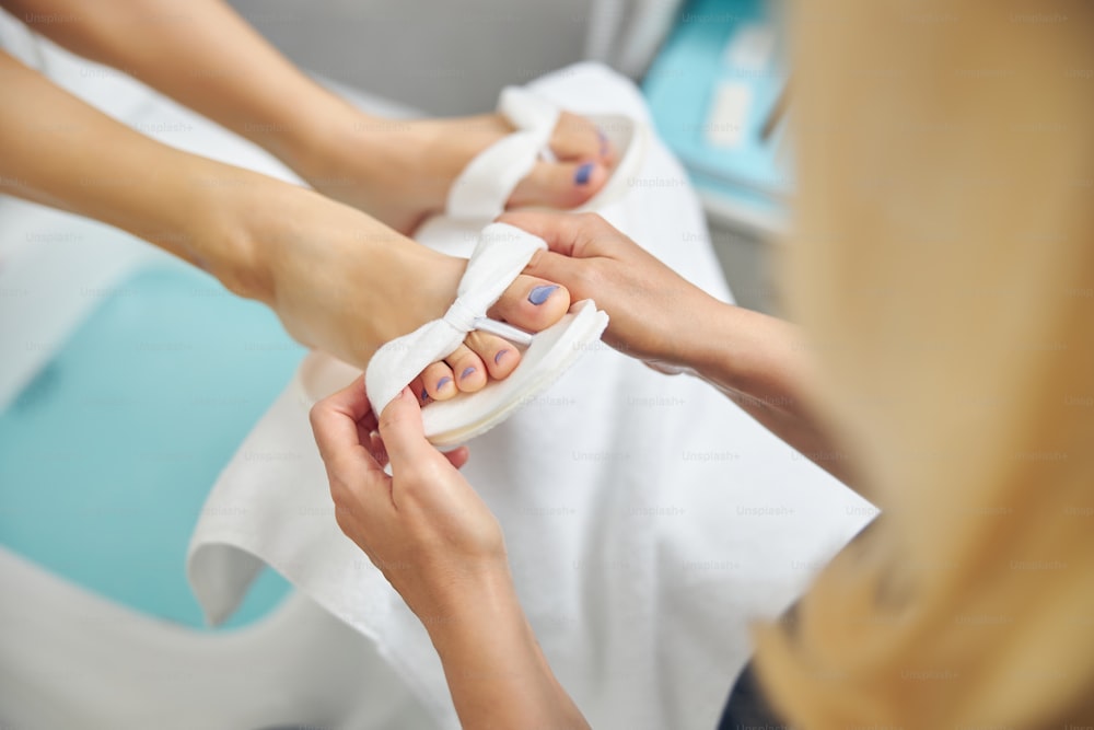 Vista superior de perto da senhora que cuida dos pés femininos após a pedicure no salão de spa