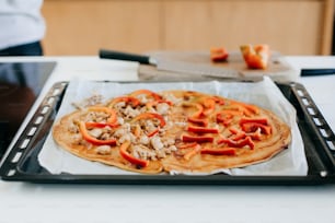 Pollo arrosto e peperoni su pasta rotonda con ketchup per pizza su cucina bianca moderna. Processo di preparazione della pizza fatta in casa, ingredienti da vicino. Concetto di cucina casalinga