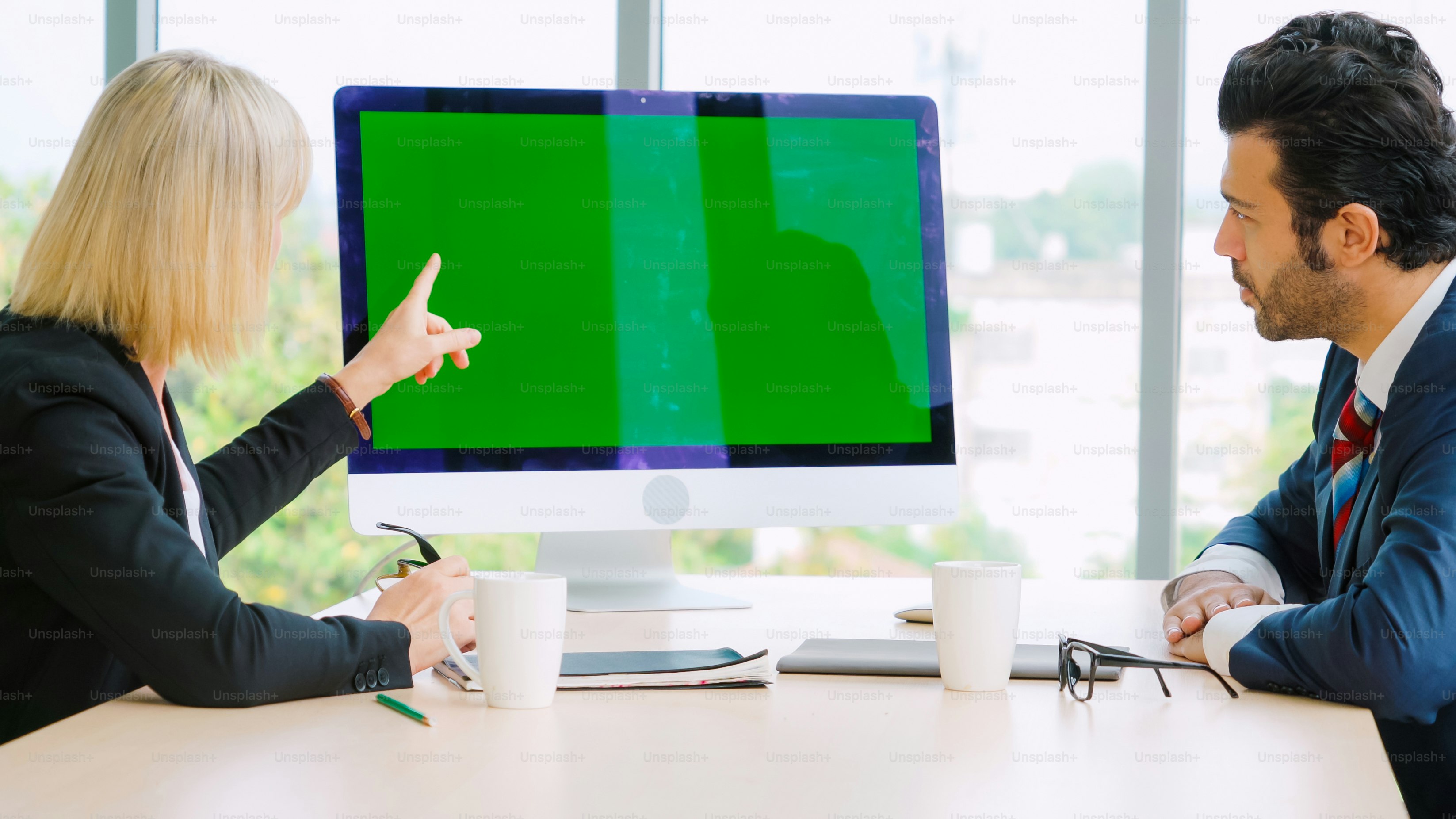 Gente de negocios en la sala de conferencias con pantalla verde chroma key TV o computadora en la mesa de la oficina. Grupo diverso de hombres y mujeres de negocios en reunión en videoconferencia.