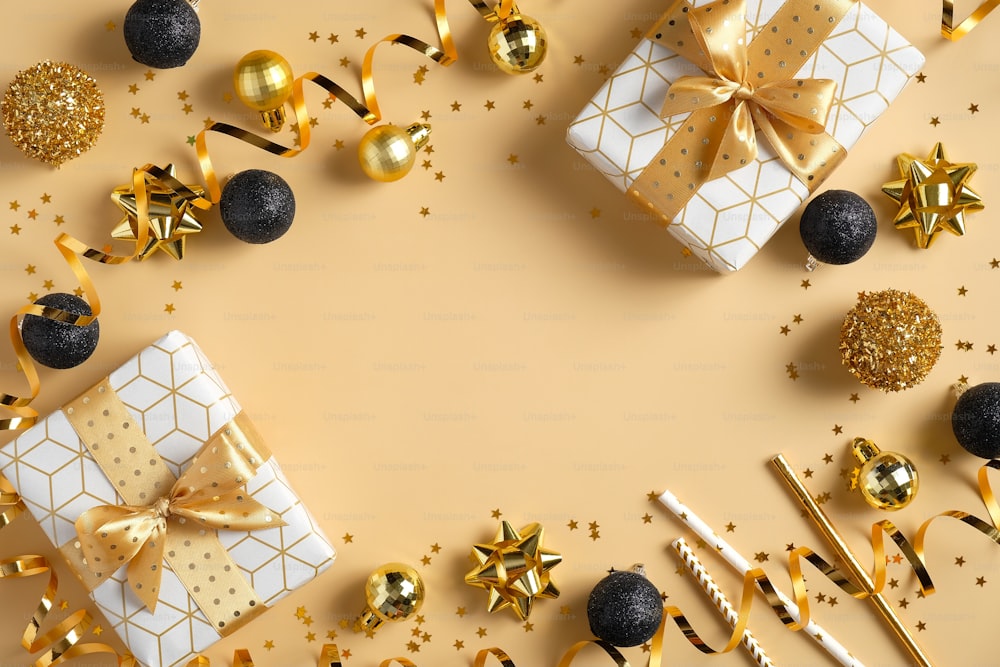 Composizione cornice di Natale o Capodanno. Decorazioni natalizie nei colori oro e nero e scatole regalo su sfondo dorato con spazio di copia per testo. Posa piatta, vista dall'alto.