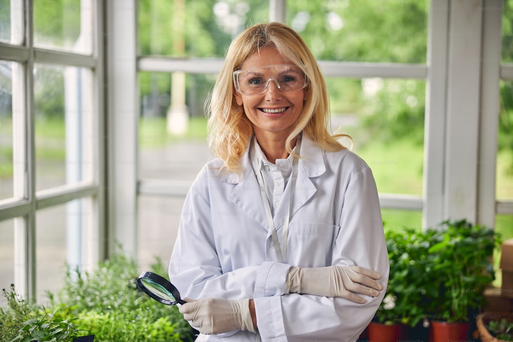 Front view of a smiling attractive female botanist in gloves looking in front of her