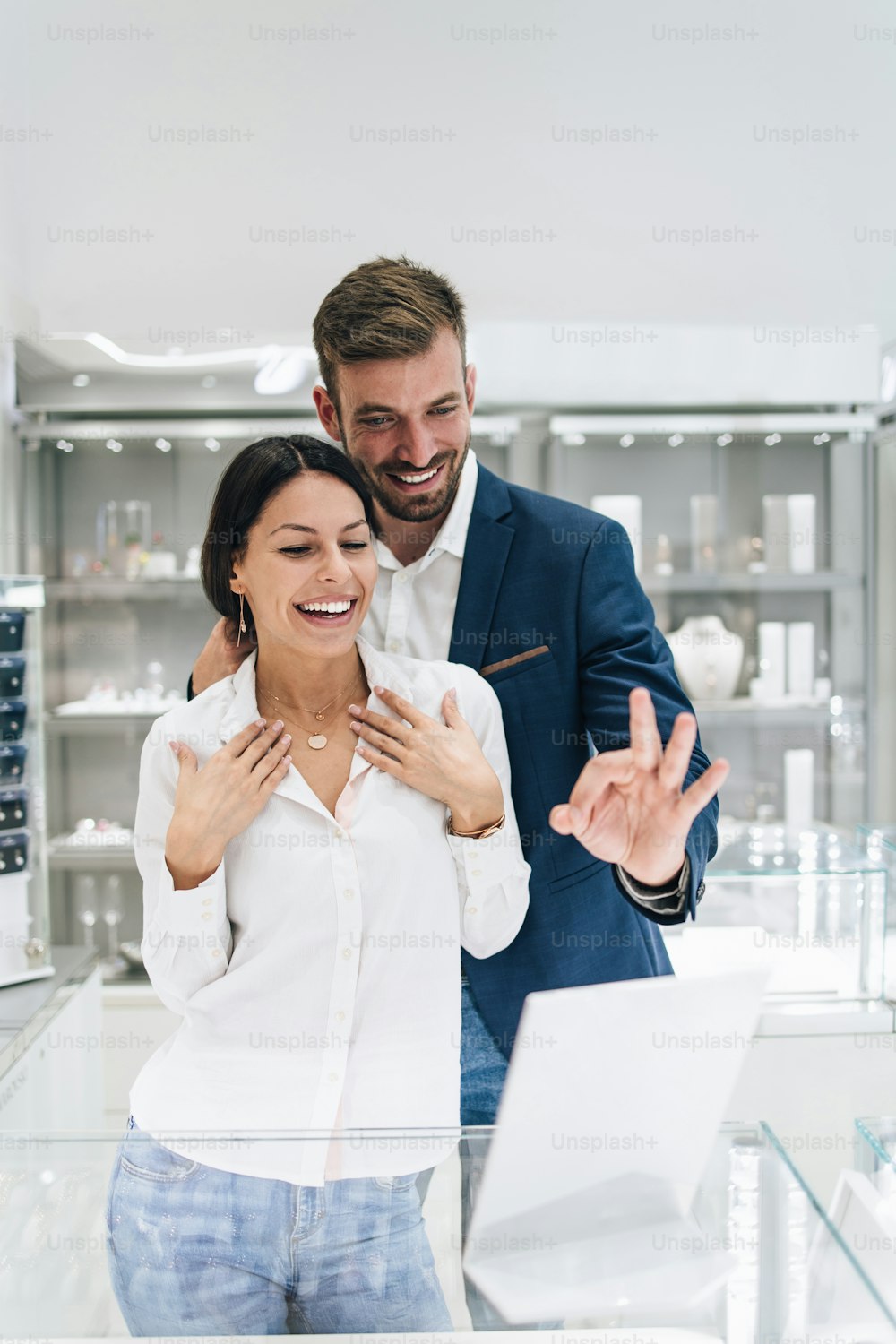 Bella coppia che si diverte a fare shopping in una gioielleria moderna. Giovane donna prova splendida collana e orecchini.