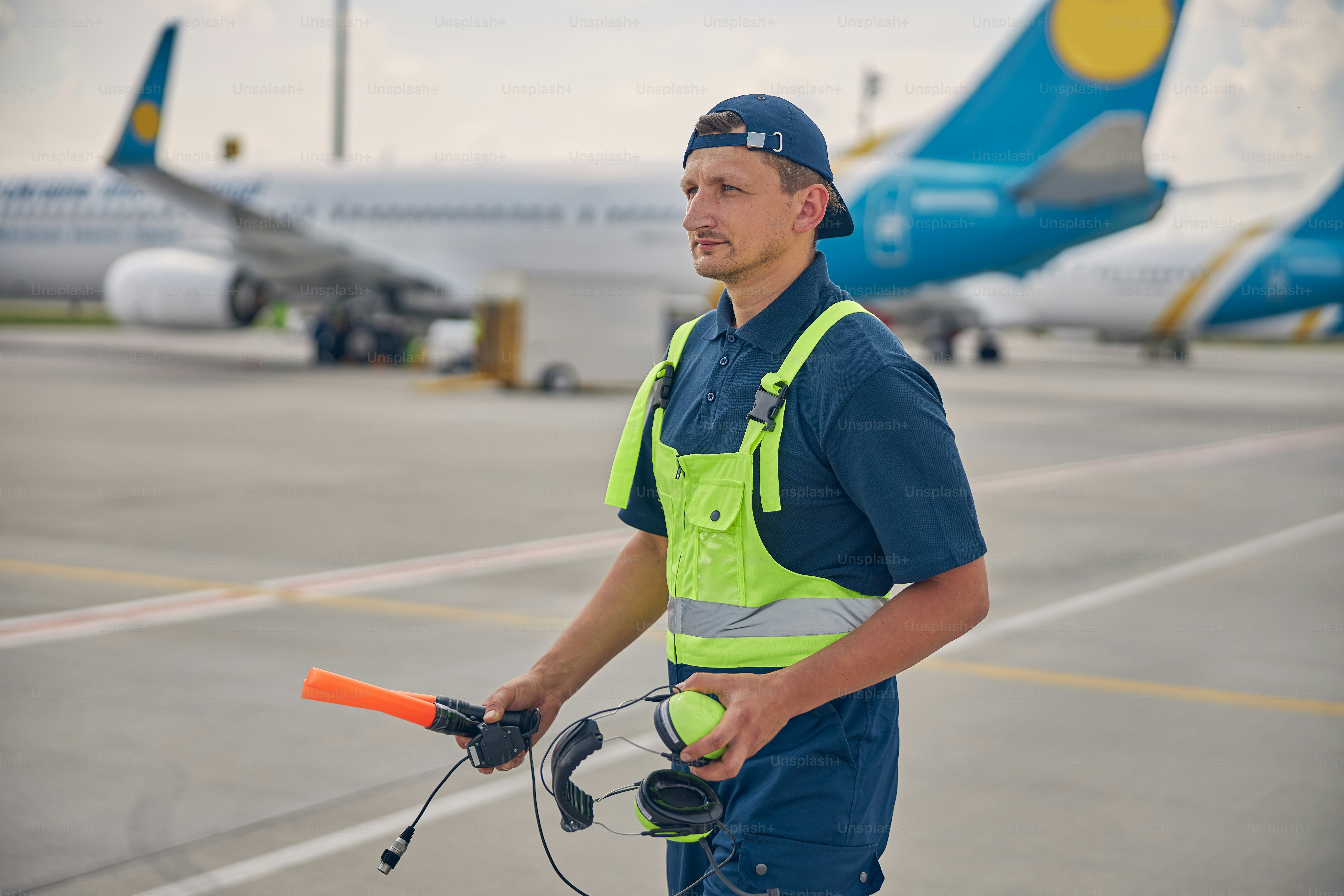 Front view of a serious Caucasian airport worker in noise-canceling ...