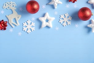 Fond de Noël bleu élégant avec des boules rouges, des décorations de Noël, des rennes Rudolph, des flocons de neige blancs, des étoiles de confettis. Pose à plat, vue de dessus. Noël, Nouvel An, concept de vacances d’hiver.