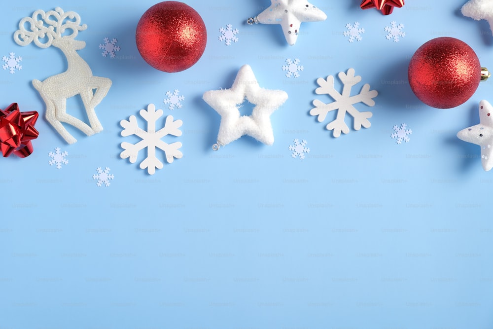 Elegant Blue Christmas background with red balls, Xmas decorations, Rudolph reindeer, white snowflakes, confetti stars. Flat lay, top view. Christmas, New Year, winter holidays concept.
