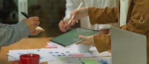 Cropped shot of office workers consulting on their project with mock up digital tablet and paperwork in meeting room