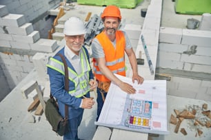 Top view of two smiling adult Caucasian men in safety helmets posing for the camera