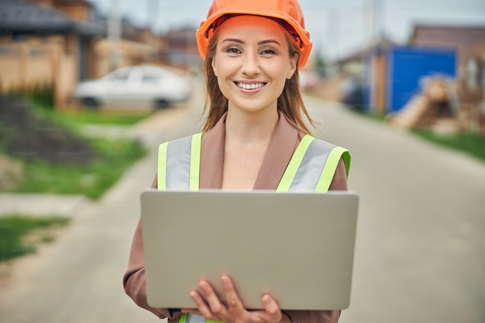 Close up portrait of a smiling pleased female constructor standing in the middle of the road