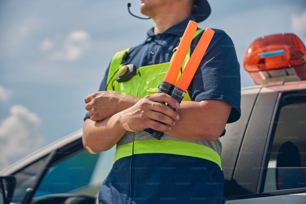 Cropped photo of a male worker in the safety overalls leaning his back against the car