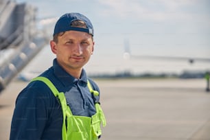 Ritratto ravvicinato di un giovane lavoratore aeroportuale con un berretto che guarda davanti a sé