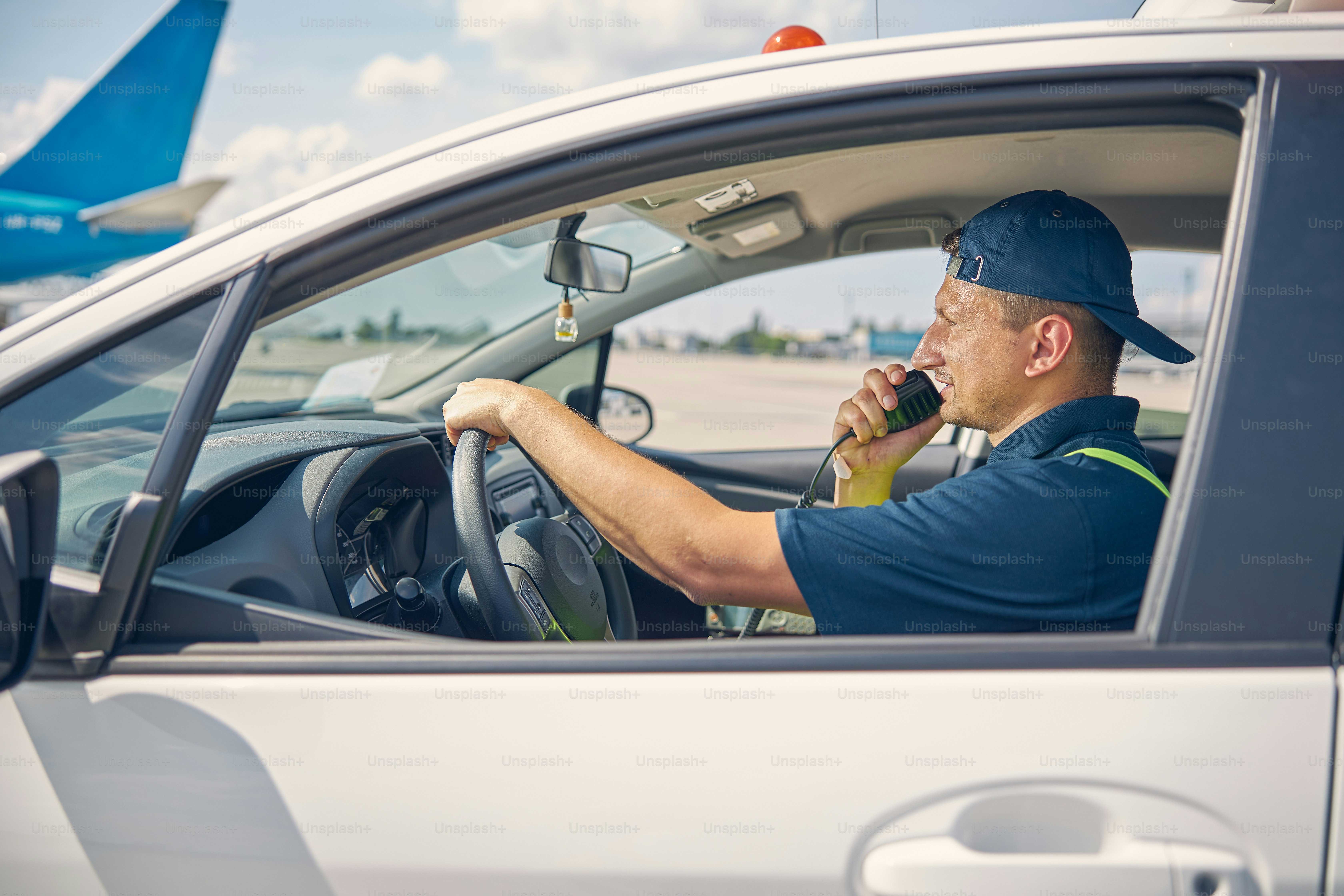Side view of a serious ground vehicle operator in a cap speaking into the microphone