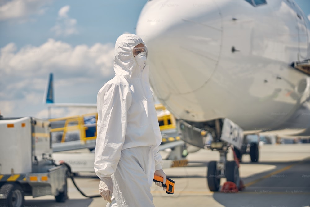 防護服を着た若い白人女性が飛行場を横切って歩いている側面図