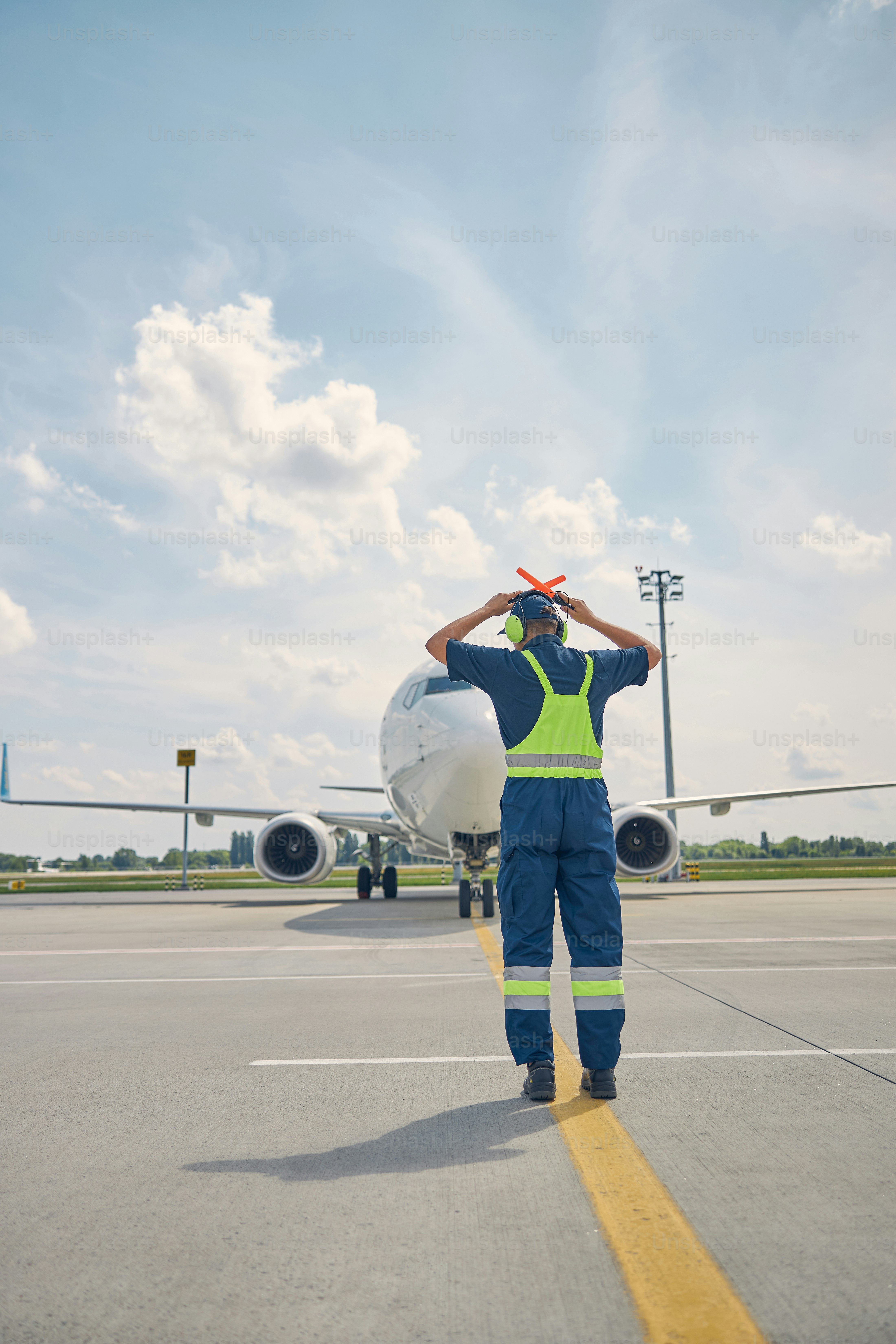 Front view of a serious Caucasian airport worker in noise-canceling ...