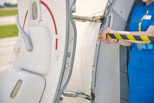 Foto ritagliata di una donna che rimuove il nastro della barriera all'ingresso di un aereo