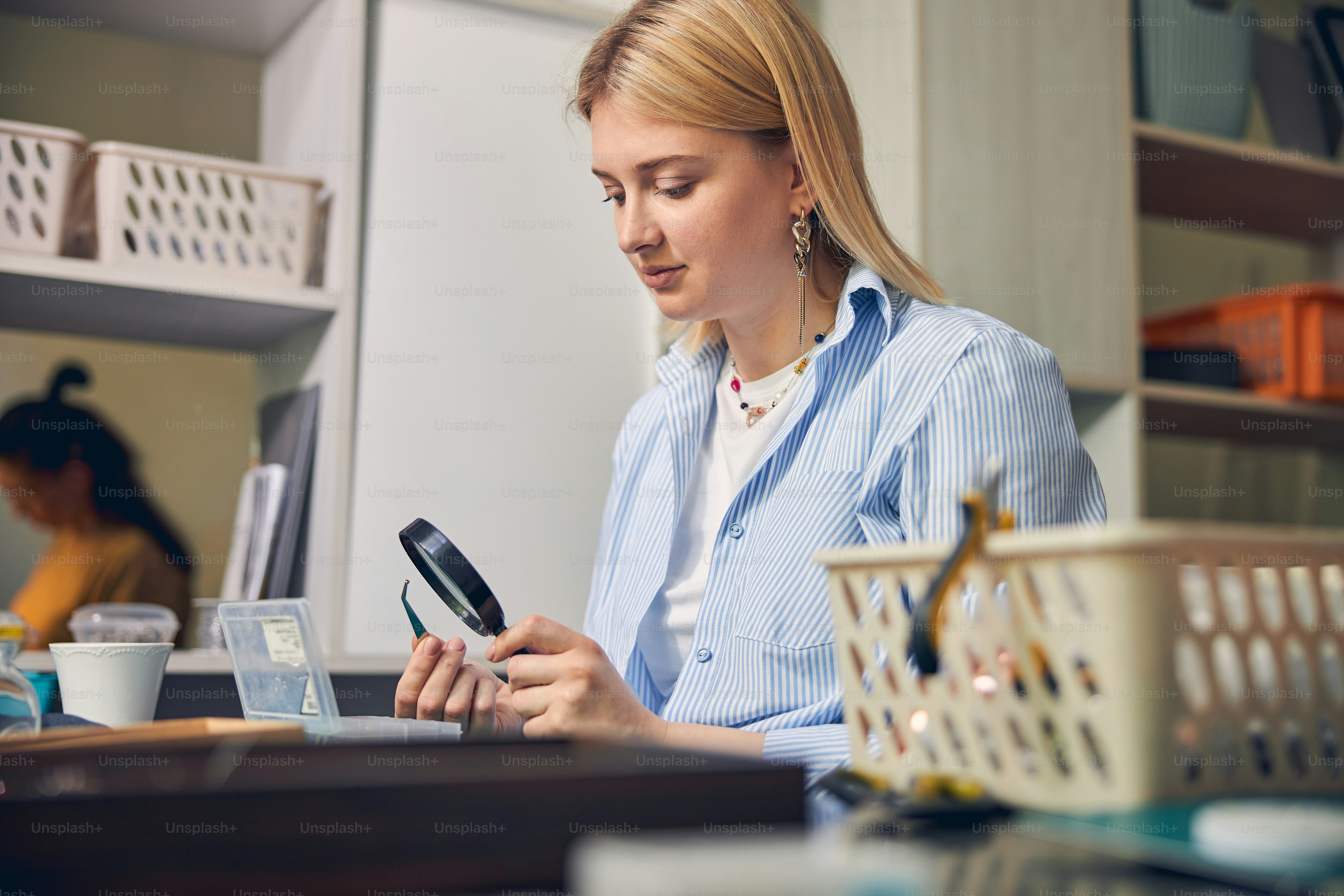 Bijouterie expert holding a bead with tongs while looking through the loupe