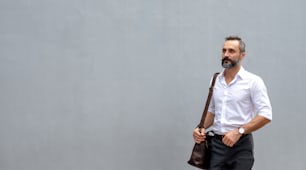 Portrait of Handsome beard guy carrying leather briefcase walking on city street