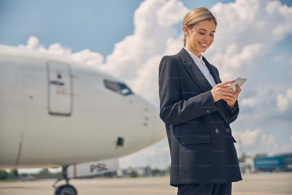 Low angle of a focused female with a gadget in her hand standing at the airport