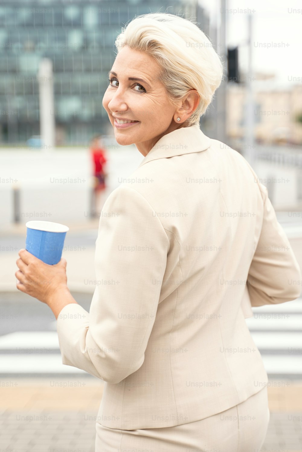 Elegant businesswoman with cup of coffee posing outdoor.