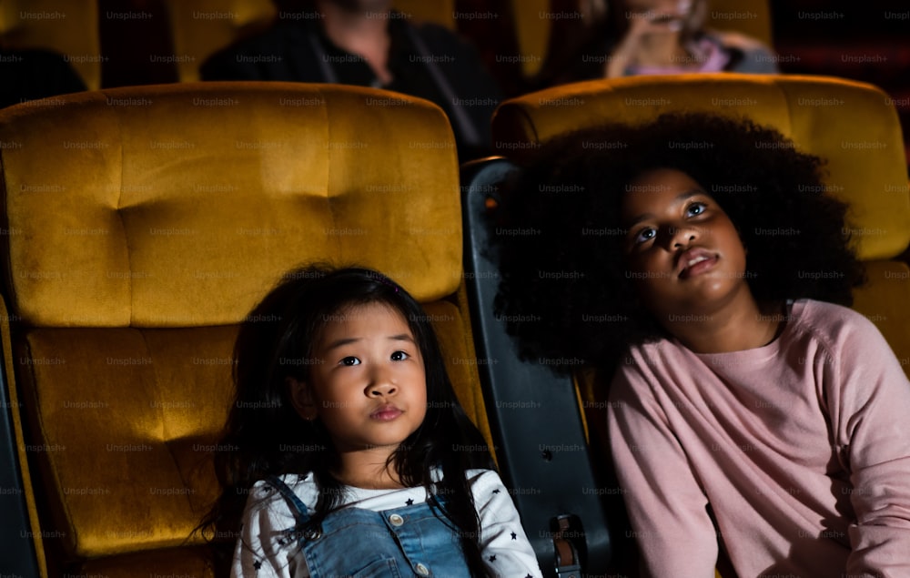 Due bambini africani e asiatici che si divertono e si divertono a guardare film nel cinema