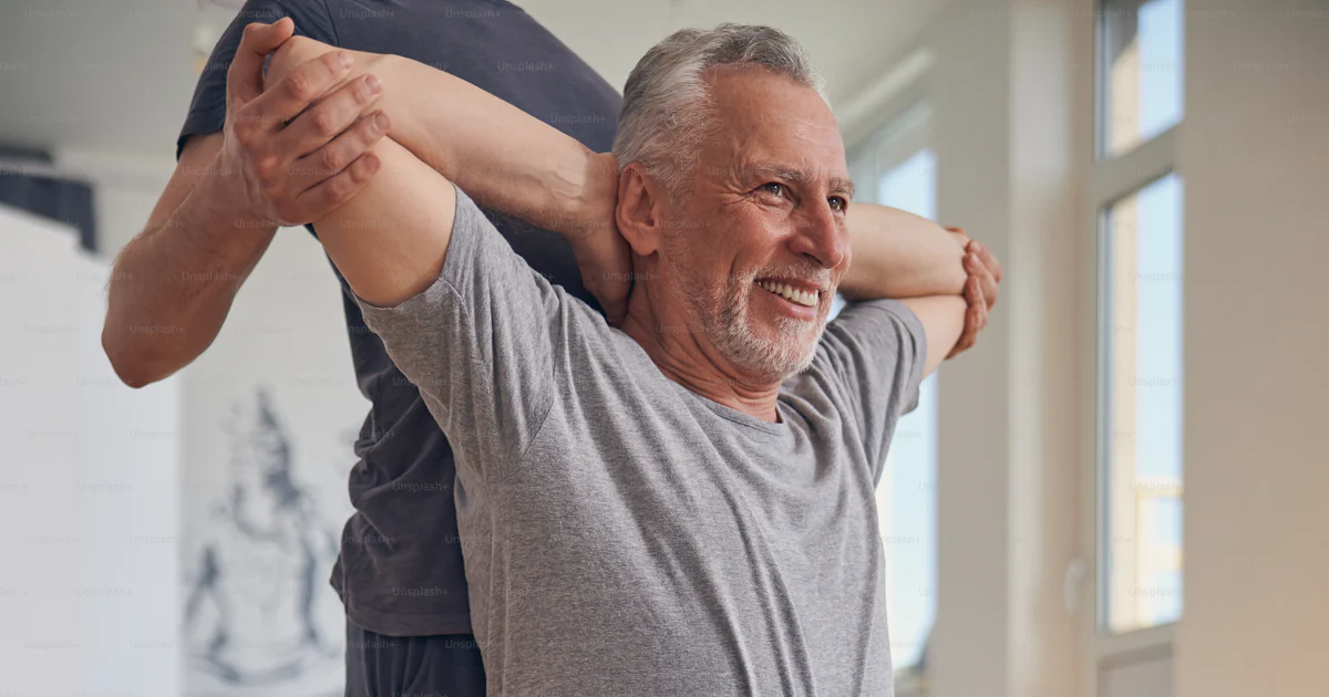 Beginner yogi doing the behind head chest stretch exercise assisted by ...